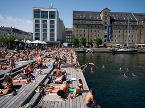 Locals and tourists enjoy the warm weather at Ofelia Square, in front of the National Theatre in Copenhagen, Denmark, on July 25, 2019.
