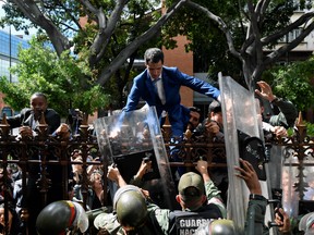 Venezuelan opposition leader and self-proclaimed acting president Juan Guaido is helped to climb a railing in an attempt to reach the National Assembly building in Caracas, on January 5, 2020.