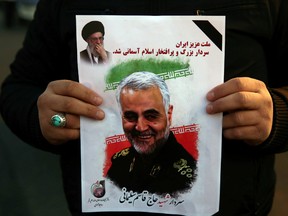 A man holds a picture of late Iranian Major-General Qassem Soleimani, as people celebrate in the street after Iran launched missiles at U.S.-led forces in Iraq, in Tehran, Iran, on Jan. 8, 2020.