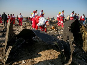 Red Crescent workers check the debris from the Ukraine International Airlines passenger jet that crashed after take-off from Iran's Imam Khomeini airport, on the outskirts of Tehran, on Jan. 8, 2020.