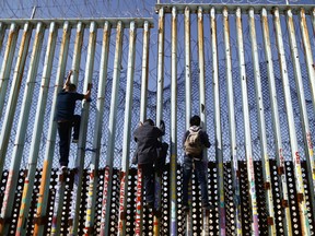 Men climb the border barrier to get a view, before climbing back down, on the U.S.-Mexico border barrier on the beach, on March 30, 2019 in Tijuana, Mexico.