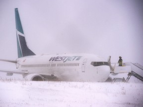 A firefighter stands on the steps of a Westjet aircraft that skidded off the runway at Halifax Stanfield International Airport on Sunday, Jan. 5, 2020.
