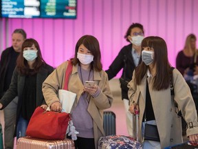 Passengers wear protective masks to protect against the spread of the Coronavirus as they arrive at the Los Angeles International Airport, California, on Jan. 22, 2020.