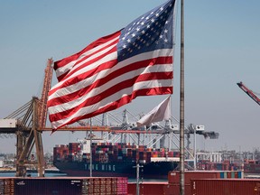 The U.S. flag flies over a container ship unloading its cargo from Asia, at the Port of Long Beach, Calif., on Aug. 1, 2019.