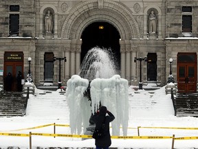 A man takes a photo of a frozen fountain outside the B.C. Legislature in Victoria, B.C.,  on Jan. 15, 2020.