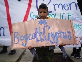 child holds a placard as activists march from the Cypriot Embassy to the Foreign Office on January 6, 2020 in London, England.