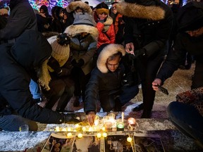 Mourners place candles and photographs during a vigil for those who were among the 176 people who were killed when Ukraine International Airlines Flight PS752 crashed after takeoff near Tehran, Iran, outside the Alberta Legislature Building in Edmonton on Wednesday, Jan. 8, 2020.