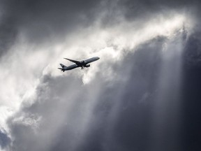 An Air Canada plane flies underneath dark clouds illuminated by some sun rays above Frankfurt, Germany, Thursday, March 2, 2017. Some experts say the Iran plane crash points to a glaring gap in rules around flight security, with states lacking incentives to close their own airspace and global agencies lacking the authority to preempt future tragedies.