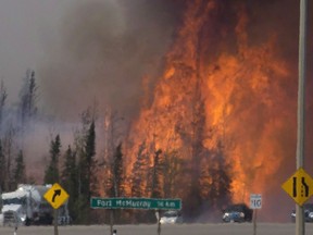 Heat waves are seen as cars and trucks try and get past a wild fire 16km south of Fort McMurray on Highway 63, Friday, May 6, 2016. The Fort McMurray fire is among Canada's biggest wildfires in the last two decades.