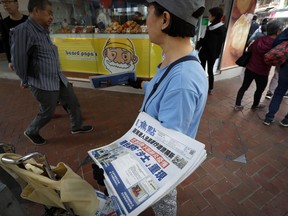 A vendor gives out copies of newspaper with a headlines of "Wuhan break out a new type of coronavirus, Hong Kong prevent SARS repeat" at a street in Hong Kong, Saturday, Jan. 11, 2020. The federal Public Health Agency says it believes Canadians are at low risk of contracting a new type of pneumonia that has killed one person and has made dozens sick in central China, but it has issued a warning to travellers to and from the city of Wuhan.