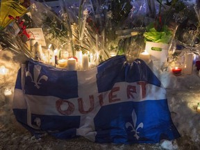 A Quebec flag with the word "Open" written on it is shown in remembrance of six victims of a shooting at mosque during a vigil in Quebec City on January 30, 2017. Events are being held Wednesday in Quebec City to mark the third anniversary of the deadly mosque shooting that claimed six lives. Organizers from the citizens group "We remember January 29" said the Quebec Islamic Cultural Centre where the killings occurred will open its doors to the community this afternoon, with a dinner and speeches later at an area church.