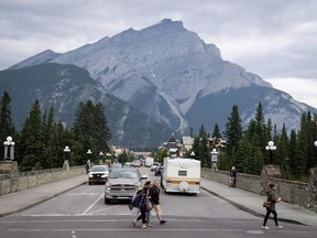 People walk across a street in Banff, Alta., in Banff National Park, Friday, July 21, 2017.