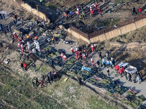 In this file photo taken on January 8, 2020 people and rescue teams are pictured amid bodies and debris after a Ukrainian plane carrying 176 passengers crashed near Imam Khomeini airport in the Iranian capital Tehran early in the morning on January 8 killing everyone on board.