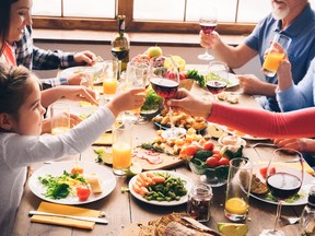 A family toasts during a meal. The adults drink alcohol while the kids drink juice.