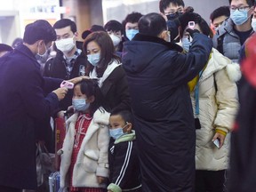 Staff members (in black) check the body temperature of passengers after a train from Wuhan arrived at Hangzhou Railway Station in Hangzhou, China's eastern Zhejiang province.