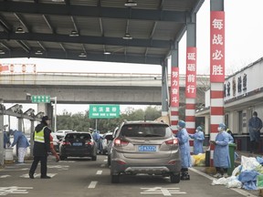 Masked health professionals and a police officer check the driver of a vehicle at a screening checkpoint on a highway toll station on the outskirts of Shanghai, China, on Tuesday, Jan. 28, 2020.