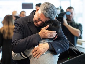 Ryan Pourjam, 13, son of Mansour Pourjam, is embraced by family friend Mahmoud Rastgou on Wednesday after a ceremony at Carleton University to honour the elder Pourjam, a biology alumnus, and doctoral student Fareed Arasteh, who died in the Ukraine International Airlines crash Jan. 8.