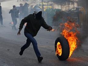 A Palestinian demonstrator rolls a burning tire during a protest against the U.S. President Donald Trump’s Middle East peace plan, in Hebron in the Israeli-occupied West Bank Jan. 31, 2020.