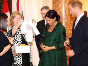 Meghan, Duchess of Sussex (2R) and Britain's Prince Harry, Duke of Sussex (R), react as they are presented with baby gifts by Canadian High Commissioner to the United Kingdom, Janice Charette (2L), at Canada House, the offices of the High Commision of Canada in the United Kingdom, during an event to mark Commonwealth Day, in central London, on March 11, 2019