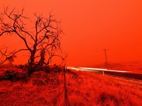 A long exposure photo shows a car pass by on a road as the sky turns red from smoke of the Snowy Valley bushfire on the outskirts of Cooma, Australia, on Jan. 4, 2020.