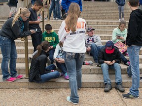 Teens check their smartphones outside the Natural History Museum in Washington on April 8, 2015.