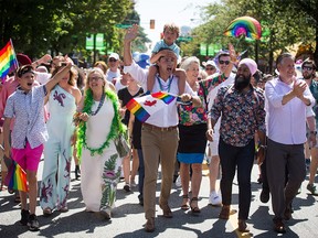 Prime Minister Justin Trudeau carries his youngest son, Hadrien, on his shoulders while marching in the Vancouver Pride Parade with his son Xavier, wife Sophie Gregoire Trudeau, second left, Green Party Leader Elizabeth May, third left, NDP Leader Jagmeet Singh, second right, and Vancouver Mayor Kennedy Stewart, right, on Aug. 4, 2019.