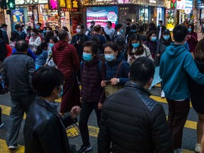 People wearing masks cross a street in a shopping district in Hong Kong on January 26, 2020, as a preventative measure following a coronavirus outbreak which began in the Chinese city of Wuhan. - Hong Kong on January 25 declared a new coronavirus outbreak as an "emergency" -- the city's highest warning tier -- as authorities ramped up measures to reduce the risk of further infections.