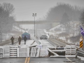 In this file photo taken on February 26, 2020 First Nations protestors walk on a bridge past their barricade on Highway 6 near Caledonia, Ontario which the protestors set up in support of the Wet'suwet'en hereditary chiefs and the Tyendinaga  Mohawks.