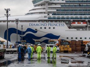 Workers gather before removing machinery stored on the dock next to the Diamond Princess cruise ship at Daikoku Pier on Feb. 13, 2020 in Yokohama, Japan.