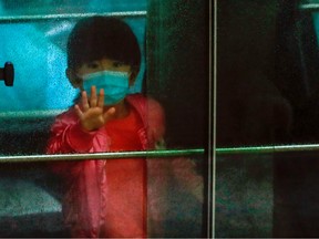A child waves as she sits in a vehicle carrying residents evacuated from a public housing building, following the outbreak of the novel coronavirus, outside Hong Mei House, at Cheung Hong Estate in Hong Kong.