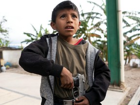 Miguel Toribio, 11, puts a pistol belonging to his father into his belt, before demonstrating newly learnt skills from military-style weapons training, to a Reuters journalist in Ayahualtempa, Mexico, February 3, 2020.