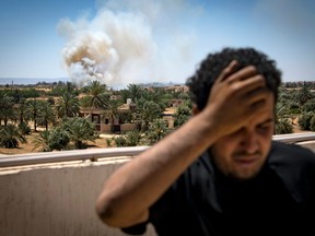 A fighter loyal to the internationally-recognized Government of National Accord (GNA) stands on a rooftop as smoke rises in the distance during clashes with forces loyal to strongman Khalifa Haftar, in Espiaa, about 40 kilometres (25 miles) south of the Libyan capital Tripoli on April 29, 2019.
