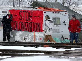 First Nations members of the Tyendinaga Mohawk Territory place a sign reading "Stop Colonization" to a camper at a blockade of train tracks servicing Via Rail, as part of a protest against British Columbia's Coastal GasLink pipeline, in Tyendinaga, Ontario, Canada February 13, 2020.