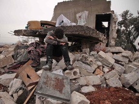 A Syrian boy cries as he sits on the rubble of the house where he lived with his displaced family in the village of Kafr Taal, Syria, after a reported pro-regime bombardment on Jan. 20, 2020.