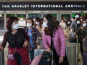 Passengers wear protective masks to protect against the spread of the coronavirus as they arrive on a flight from Asia at the Los Angeles International Airport, California, on Jan. 29, 2020.