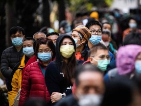 People wearing face masks line up to purchase face masks from a makeshift stall after queueing for hours following a registration process during which they were given a pre-sales ticket, in Hong Kong on Feb. 5, 2020.
