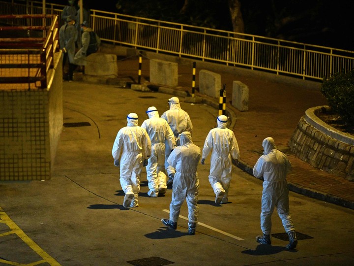  Medical personnels wearing protective suits walk in the ground of a residential estate, in Hong Kong, early on February 11, 2020, after two people in the block were confirmed to have contracted the coronavirus according to local newspaper reports.