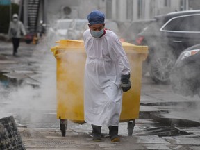 A worker carts a bin loaded with medical waste to a storage facility at the Youan Hospital in Beijing on Feb. 14, 2020.