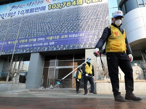 South Korean health officials spray disinfectant in front of the Daegu branch of the Shincheonji Church of Jesus in the southeastern city of Daegu on February 20, 2020 as about 40 new cases of the COVID-19 coronavirus confirmed after they attended same church services.