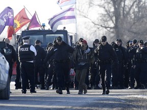Ontario Provincial Police officers lead away a man after making an arrest at a rail blockade in Tyendinaga Mohawk Territory, near Belleville, Ont., on Monday Feb. 24, 2020, as they protest in solidarity with Wet'suwet'en Nation hereditary chiefs attempting to halt construction of a natural gas pipeline on their traditional territories.