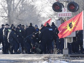 Ontario Provincial Police officers arrest a protester at a rail blockade in Tyendinaga Mohawk Territory, near Belleville, Ont., on Monday Feb. 24, 2020, as they protest in solidarity with Wet'suwet'en Nation hereditary chiefs attempting to halt construction of a natural gas pipeline on their traditional territories.