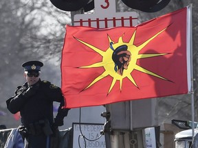 An Ontario Provincial Police officer talks on a radio after arrests were made at a rail blockade in Tyendinaga Mohawk Territory, near Belleville, Ont., on Monday Feb. 24, 2020, during a protest in solidarity with Wet'suwet'en Nation hereditary chiefs attempting to halt construction of a natural gas pipeline on their traditional territories.