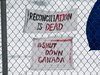 Signs posted on a fence at a railway blockade in St. Lambert, Que., on Feb. 20, 2020.