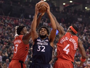 Minnesota Timberwolves centre Karl-Anthony Town (32) tries for a basket between Toronto Raptors forwards OG Anunoby (3) and Rondae Hollis-Jefferson (4) in the first half at Scotiabank Arena.