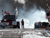 A protester stands beside smoke at the closed train tracks in Tyendinaga Mohawk Territory near Belleville, Ont., on Feb. 20, 2020.