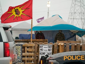 Ontario Provincial Police and First Nations protesters sit on opposite sides of a barricade on Highway 6 near Caledonia, Ont., which the protesters set up in support of Wet'suwet'en hereditary chiefs, on Feb. 26, 2020.