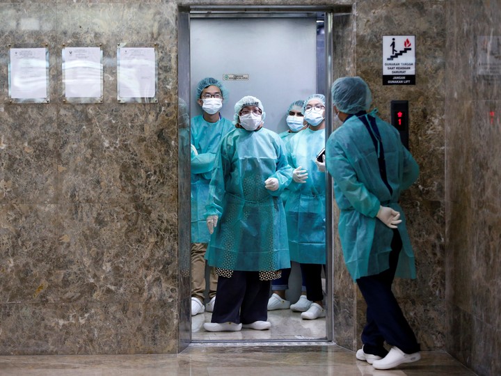  Journalists wear protective suits inside an elevator as they prepare for a media visit to Indonesian Health Ministry’s Laboratorium for Research on Infectious-Diseases, following the outbreak of the new coronavirus in China, in Jakarta, Indonesia, February 11, 2020.