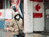 A pedestrian wears a protective mask as she walks in downtown Toronto on Feb. 26, 2020.