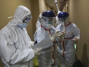 A medical worker in a protective suit writes on a tube after collecting a sample for nucleic acid tests from a suspected virus patient at a hotel being used to place people in medical isolation in Wuhan in central China's Hubei Province, Tuesday, Feb. 4, 2020. B.C. health officials believe a woman in her 50s in the Vancouver area has contracted the new coronavirus. THE CANADIAN PRESS/Chinatopix via AP
