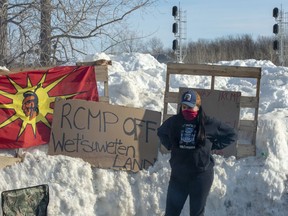 A member of the Mohawk community stands near the blockade of the commuter rail line Wednesday, February 12, 2020 in Kahnawake, Quebec.